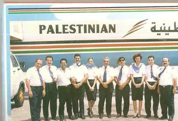 Airline pilots and cabin crew pose together in front of a Palestinian Airlines aircraft.